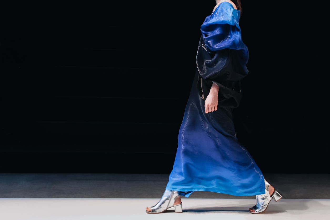 Fashion model on a walking the runway in a blue designer dress.