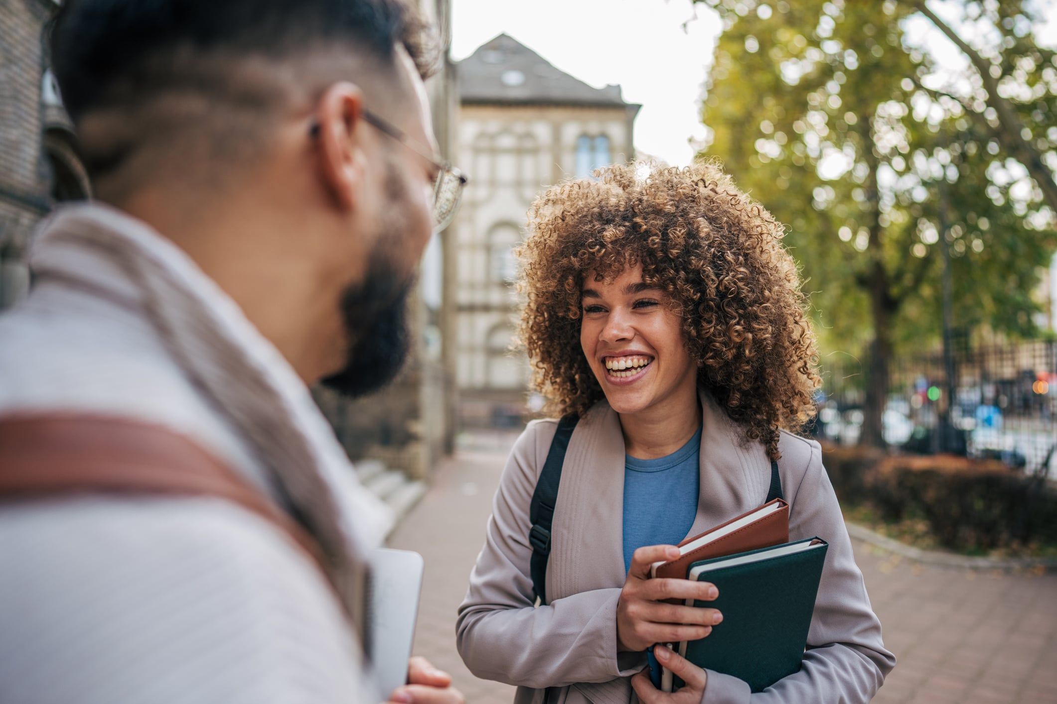 Two students, one male and one female, stand on a university campus smiling after transferring from an H-1B to an F-1 visa.