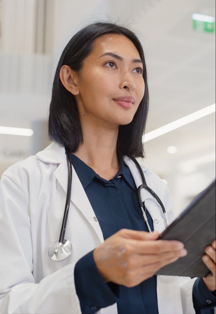 A physician holding a tablet in a bright hospital atrium