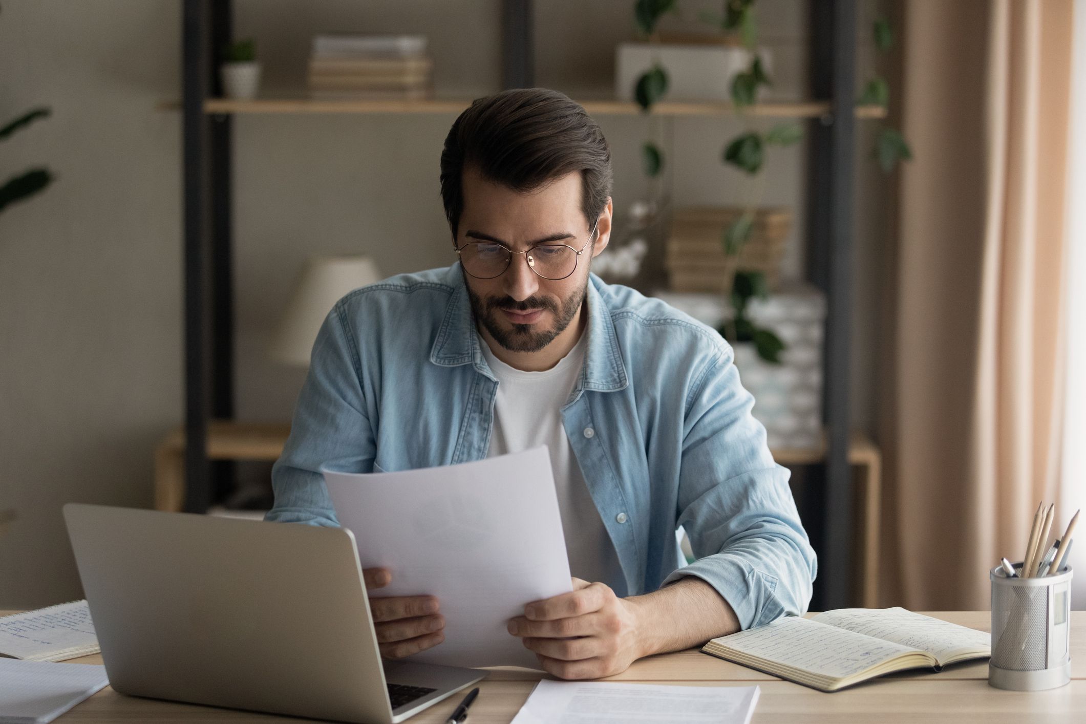 Man at a desk carefully reading a printed decision notice.