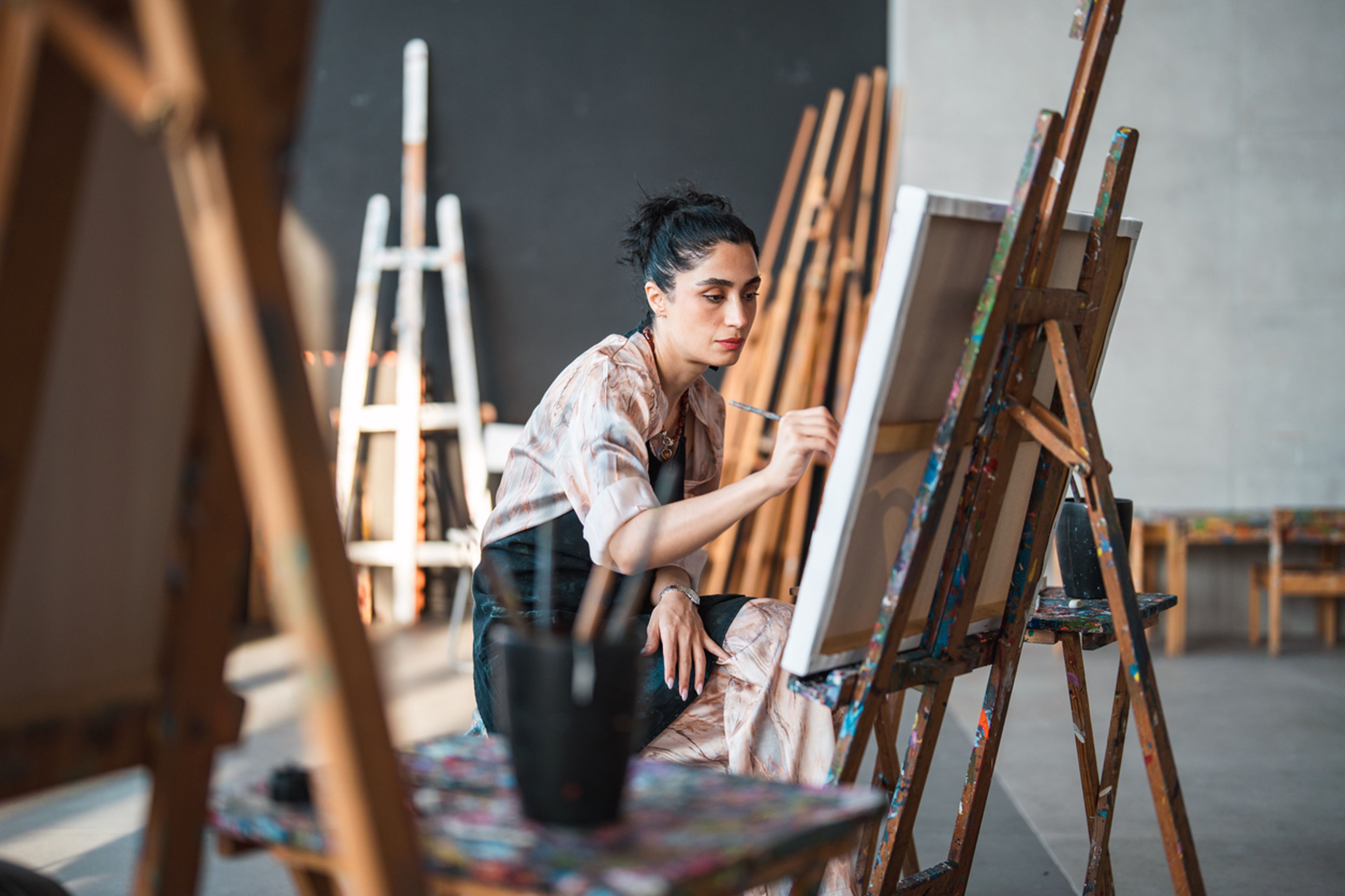 An artist painting on a canvas in her studio.