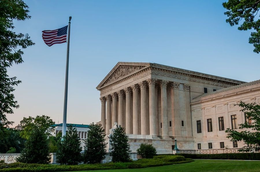 Side view of the United States Supreme Court building with an American flag flying in front.