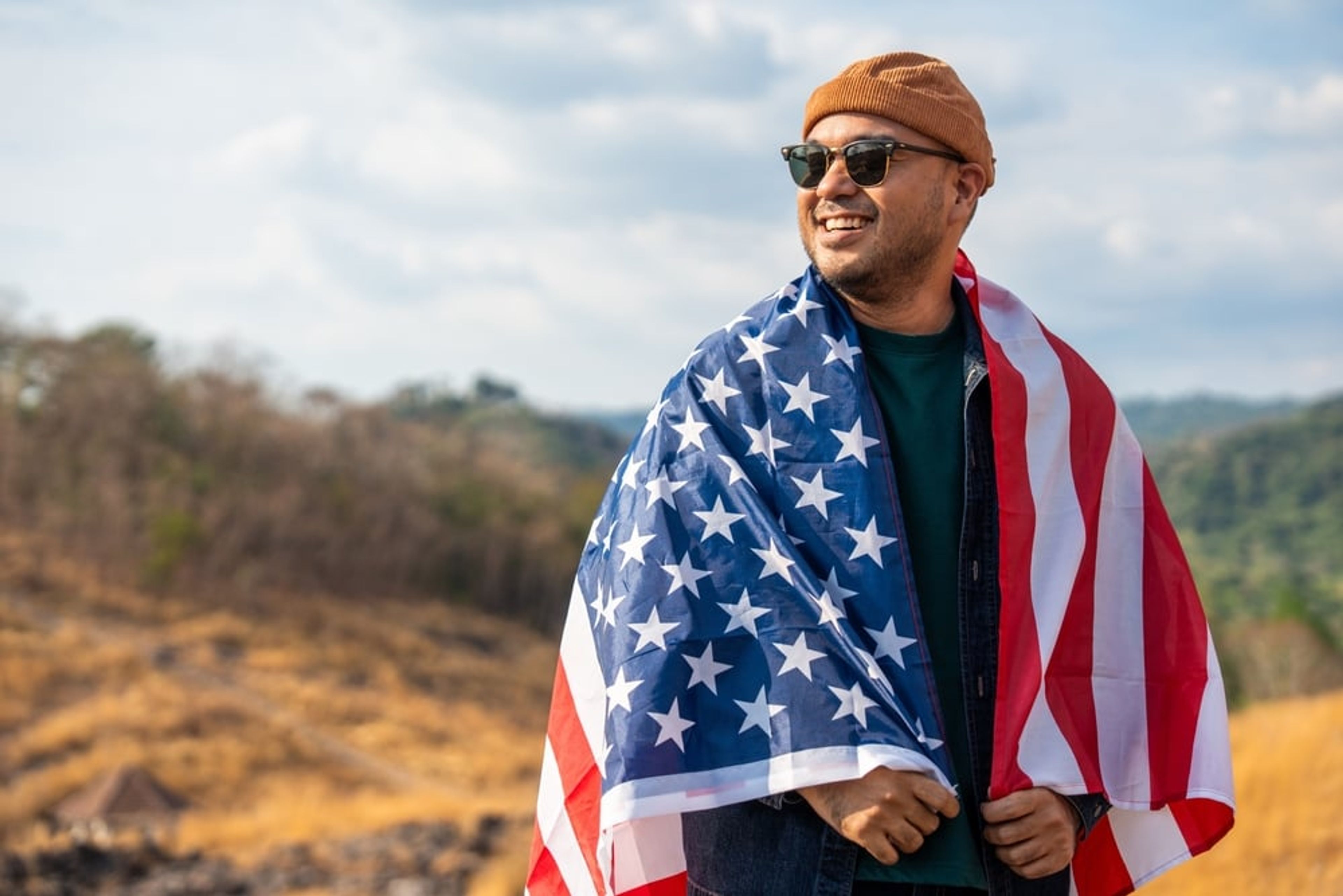 Smiling man wearing an American flag draped over his shoulders