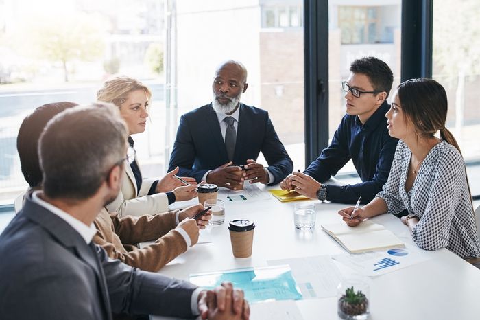 Office workers sitting around a desk in a conference room for a meeting