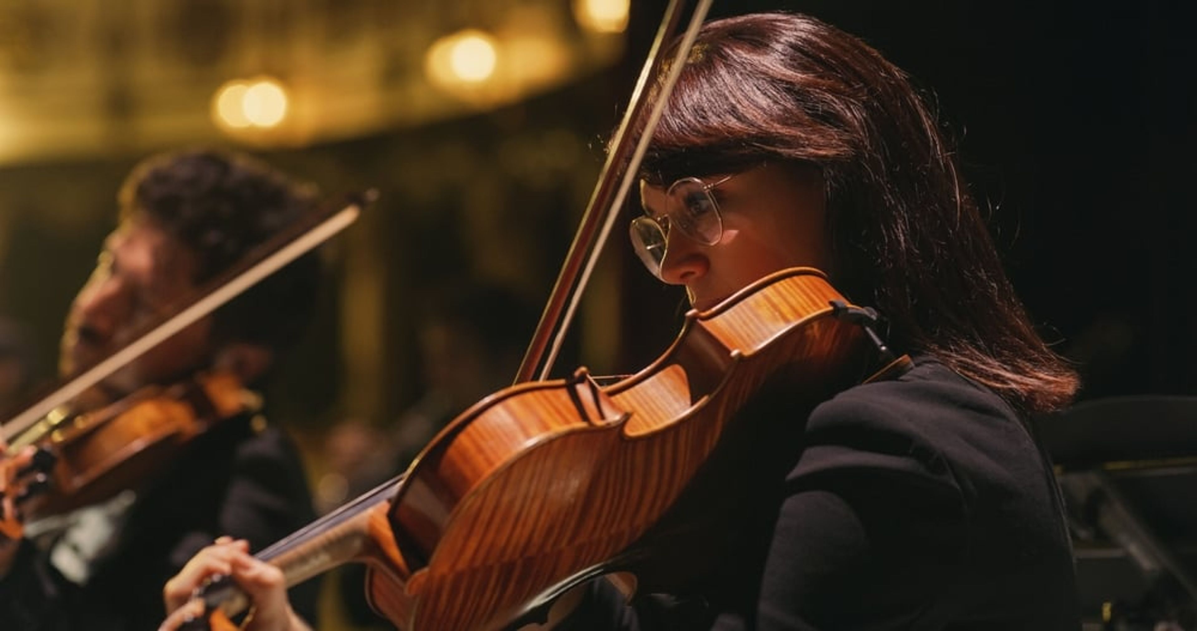 Closeup image of a violinist playing in a concert.