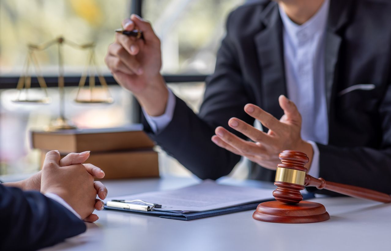 A lawyer and client are sitting at a desk discussing immigration appeal paperwork.