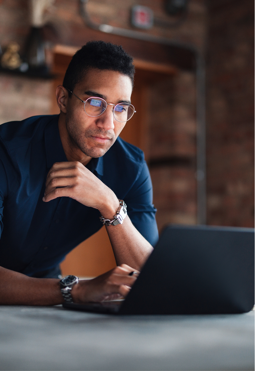 A founder working on a laptop in a brick-walled office