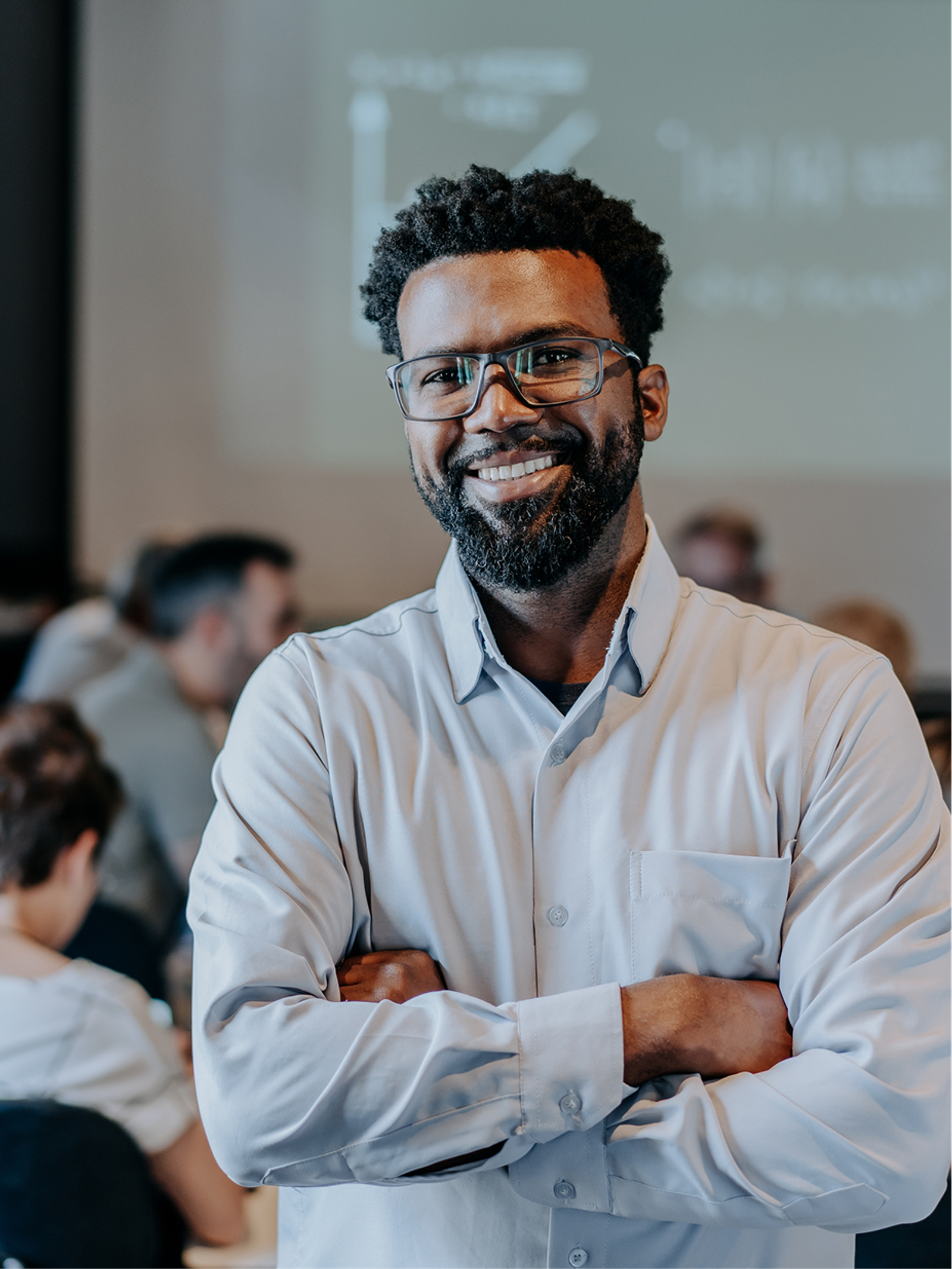 A researcher smiling with arms crossed in an academic workspace