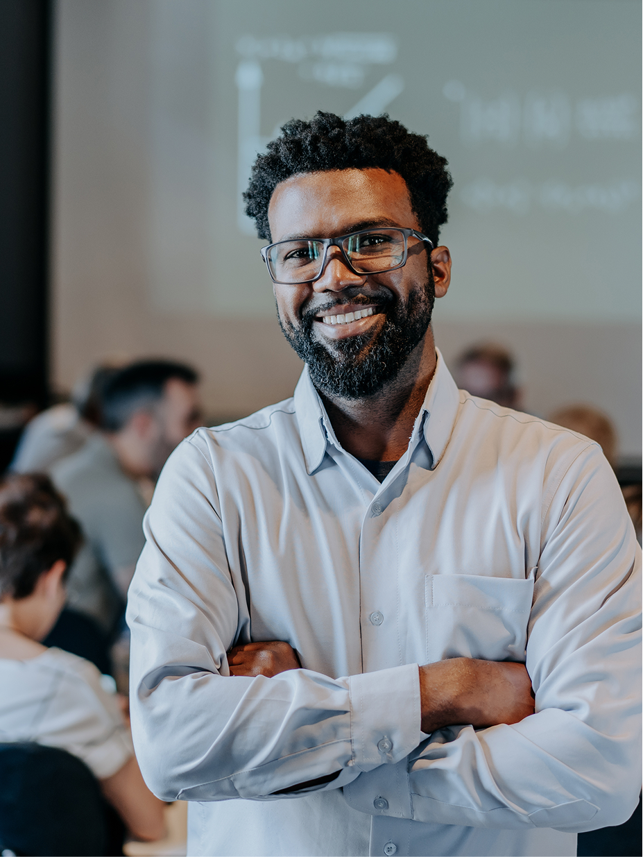 A researcher smiling with arms crossed in an academic workspace