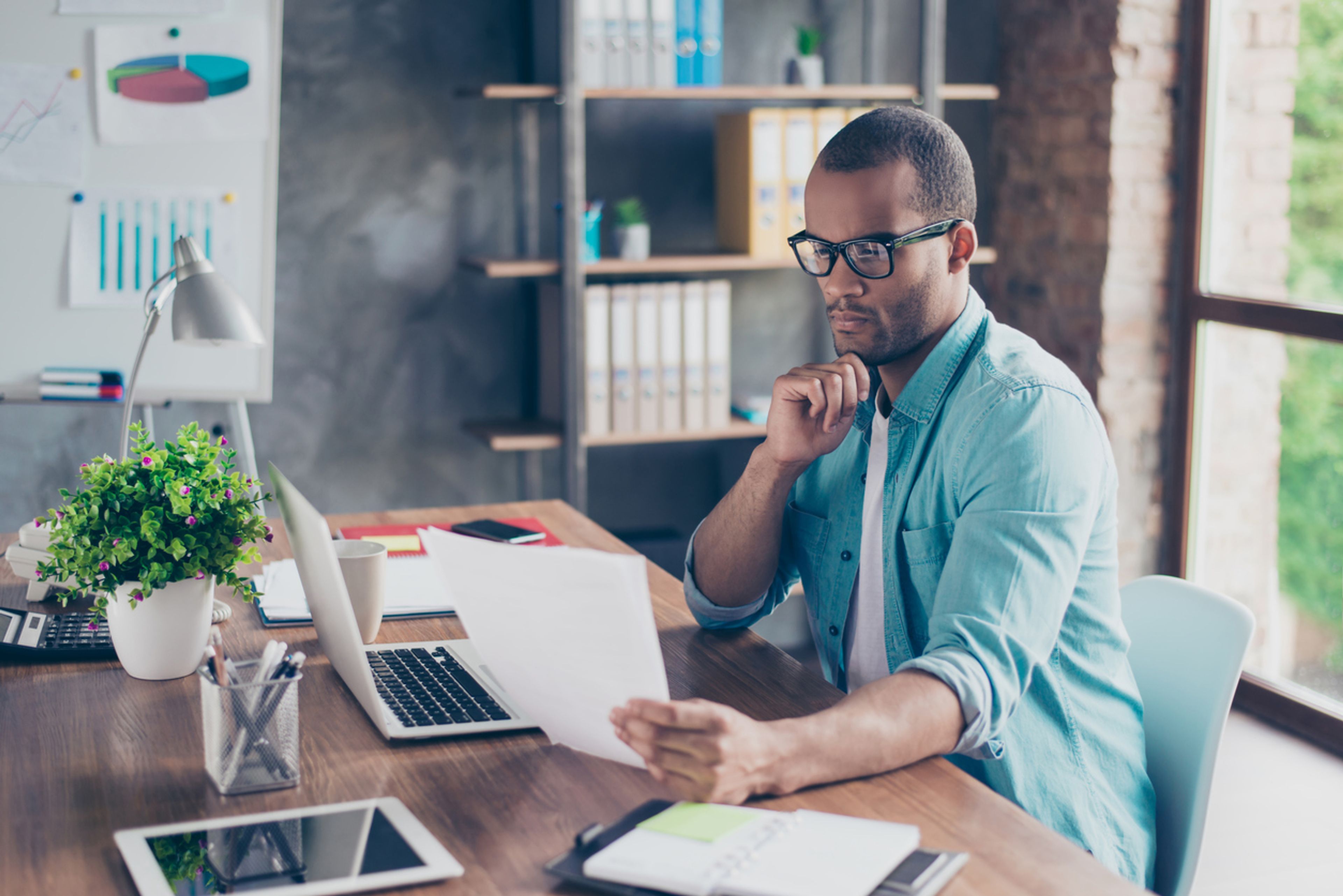 man works at desk while holding paper