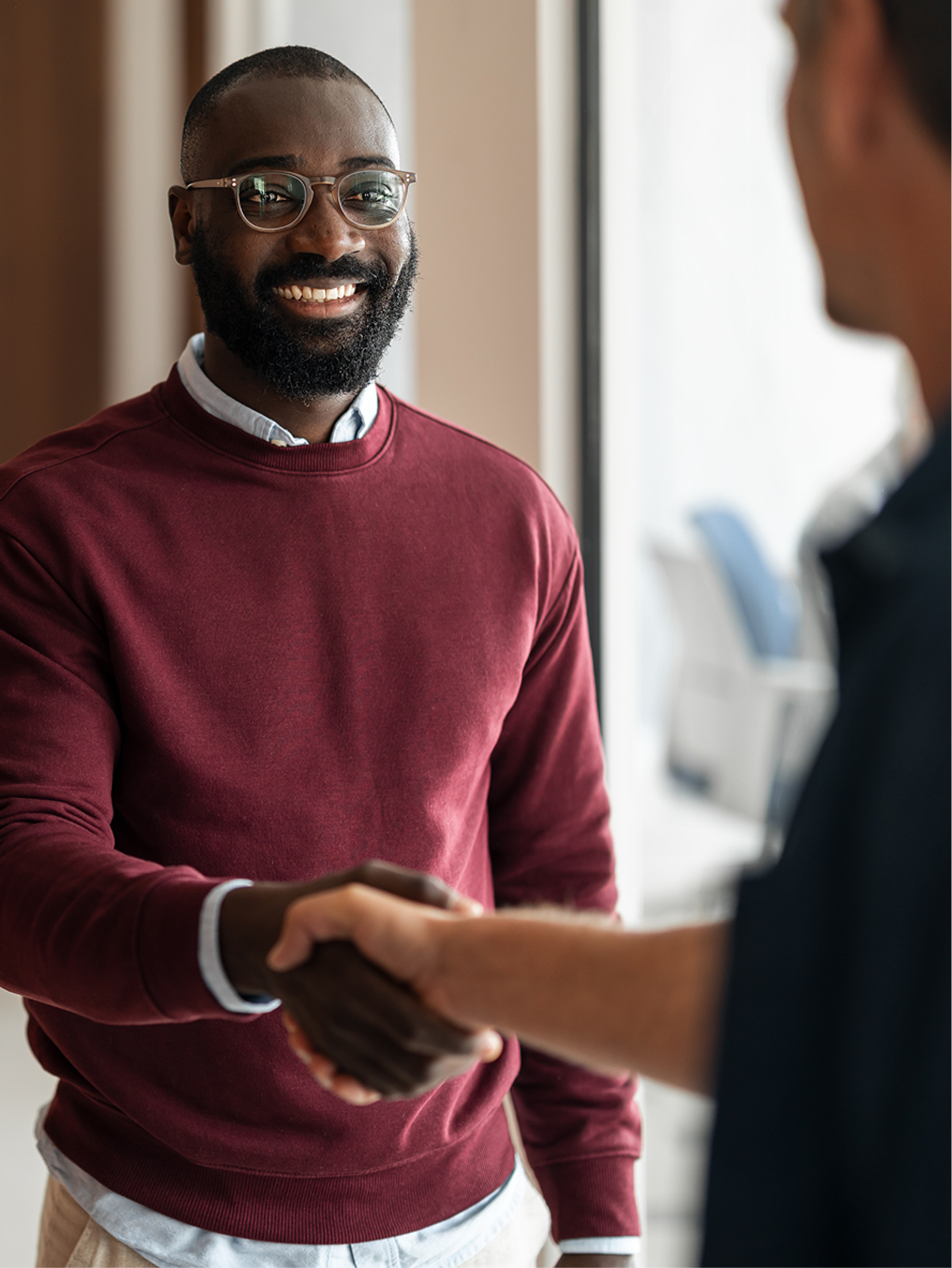 A smiling founder shaking hands with a colleague in an office