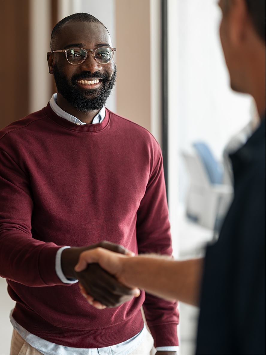 A smiling founder shaking hands with a colleague in an office