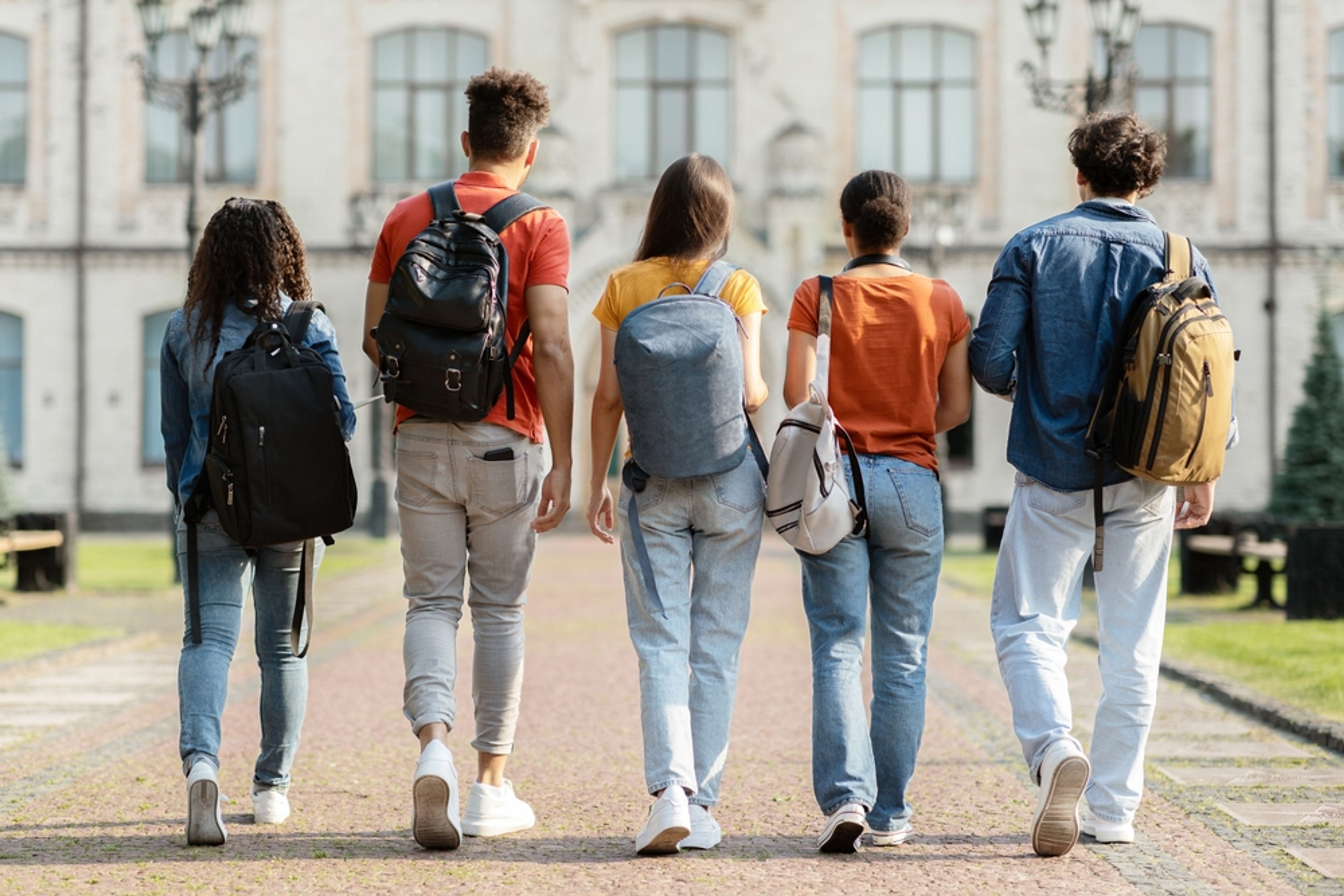 Group of five students leaving university, viewed from behind.