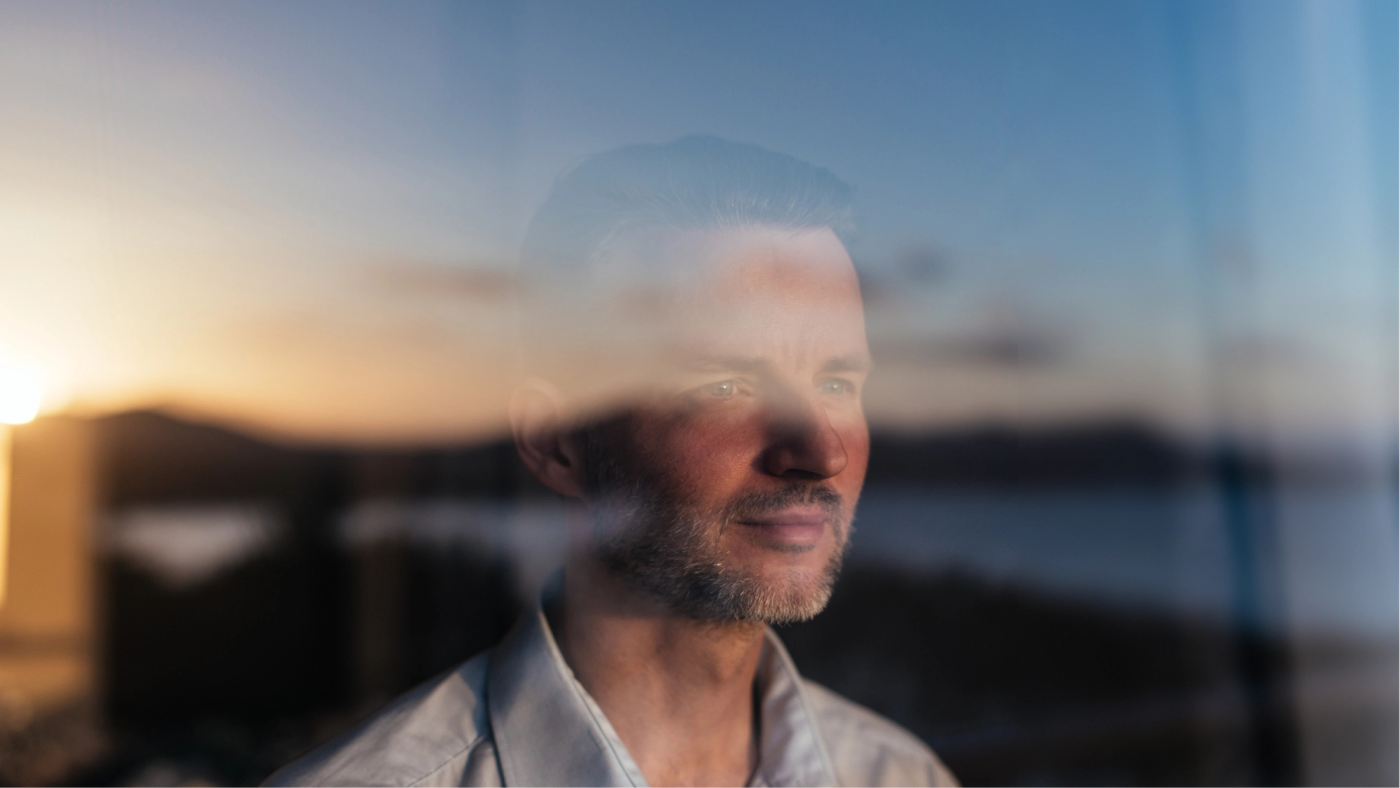 A professional looking through a window with a sunset reflection