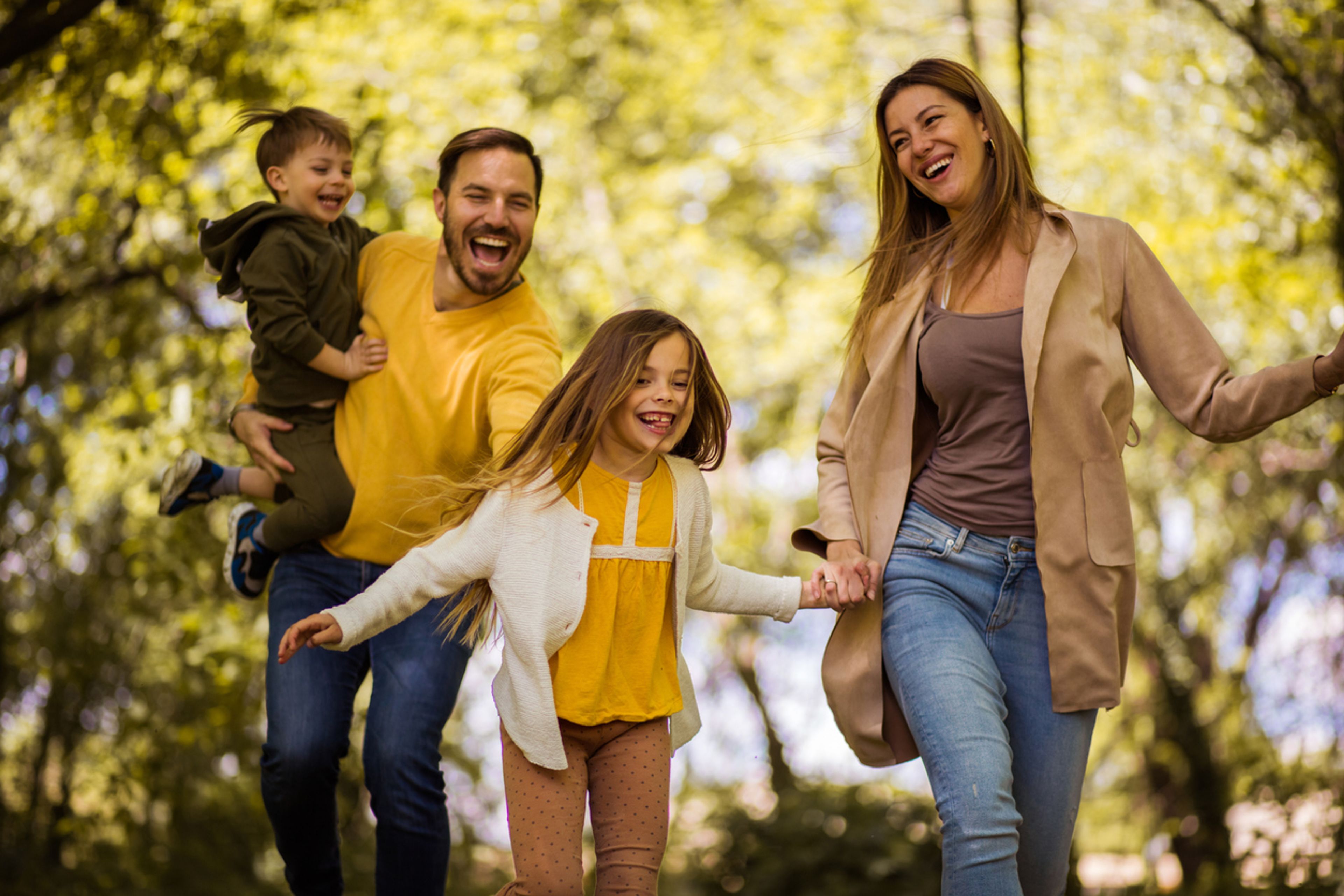 Happy parents with two young children going for a walk in the park.