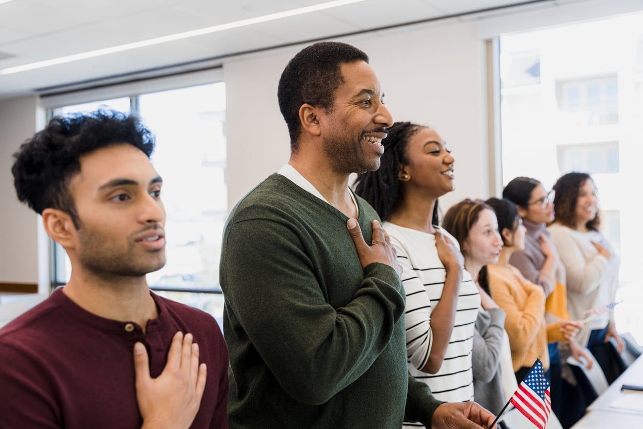 A group of people reciting the Oath of Allegiance at a naturalization ceremony.