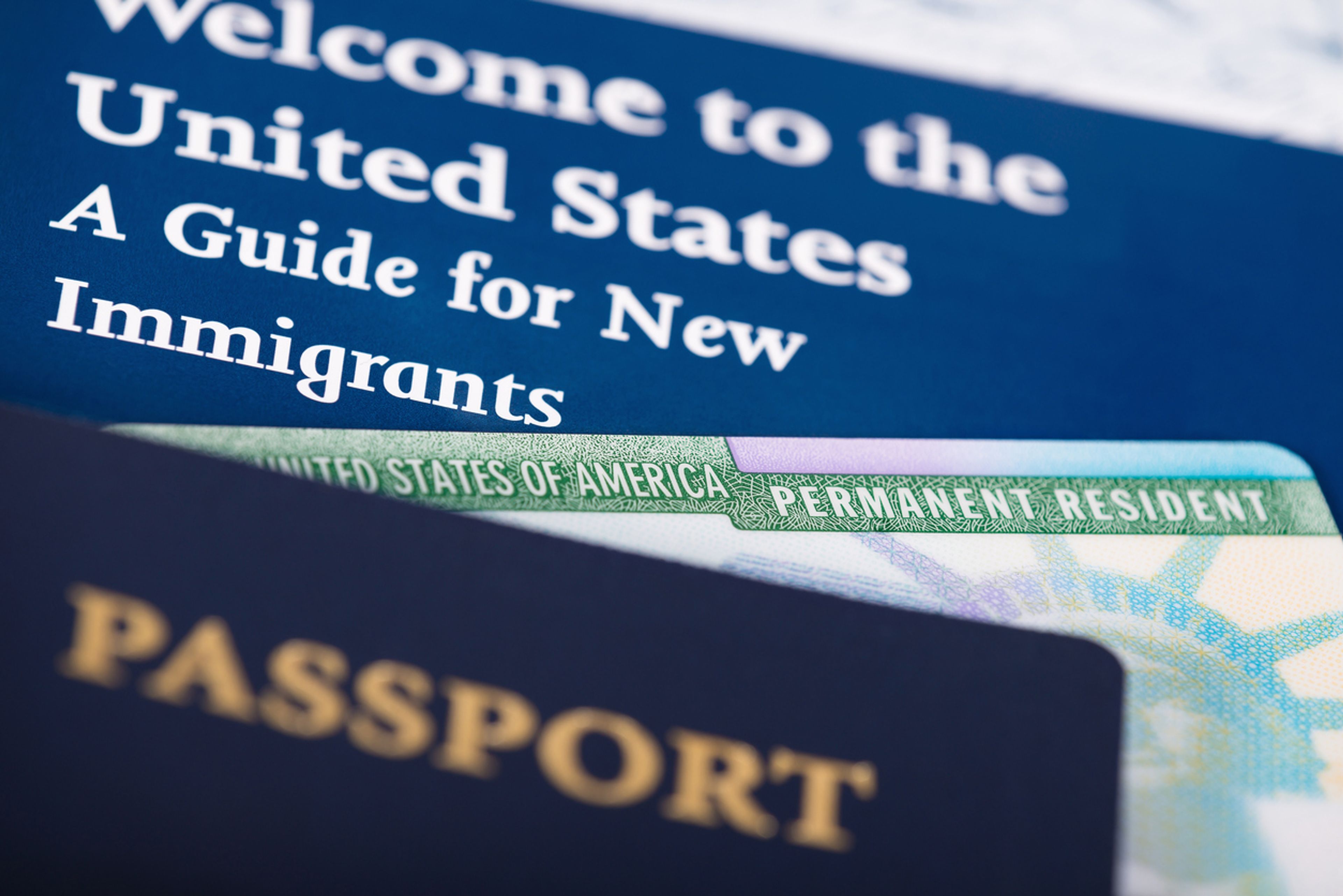 A closeup of a U.S. permanent resident card, passport, and a paper that says "Welcome to the United States"