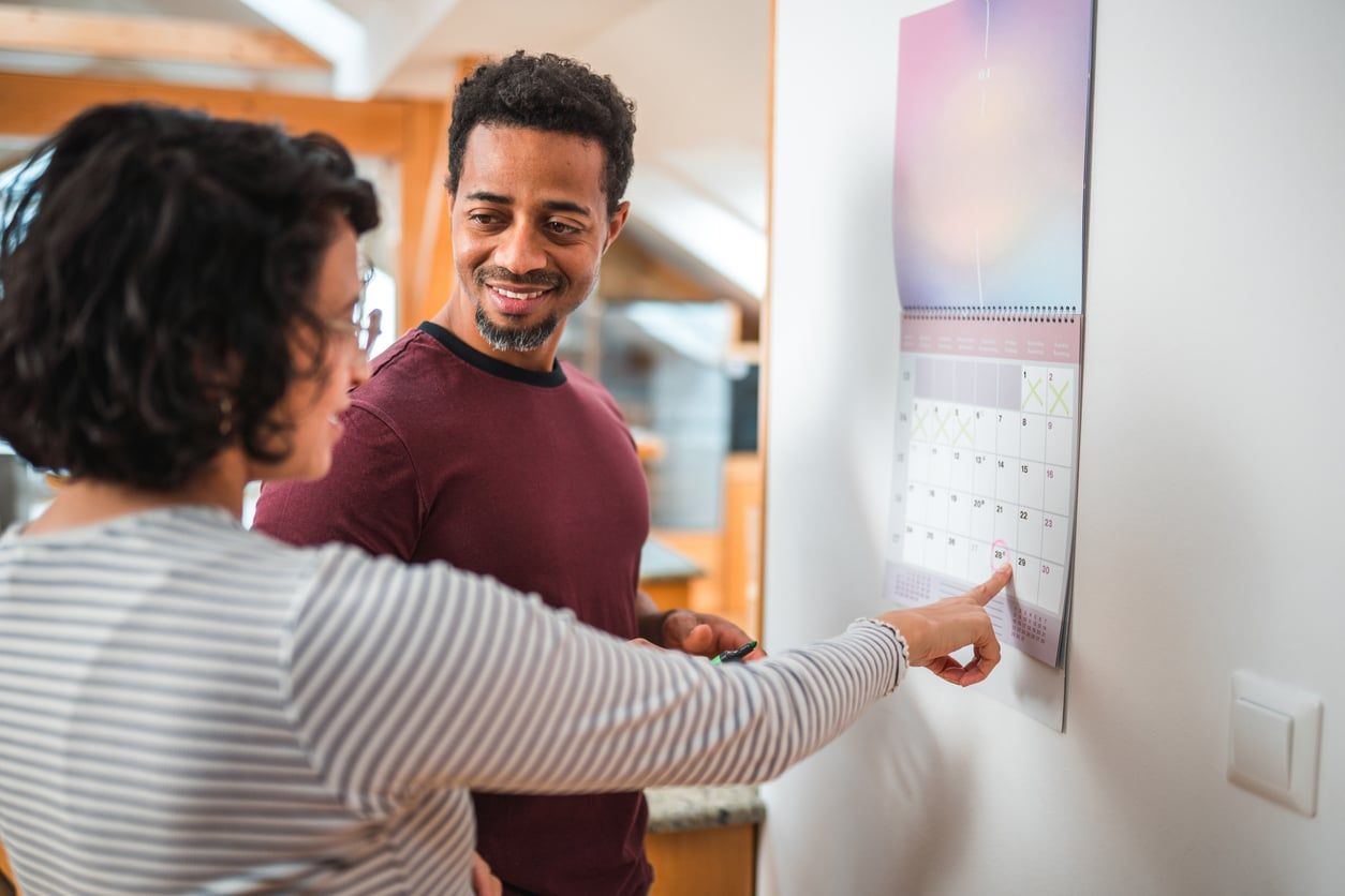 Couple looking at a calendar together with a date circled.