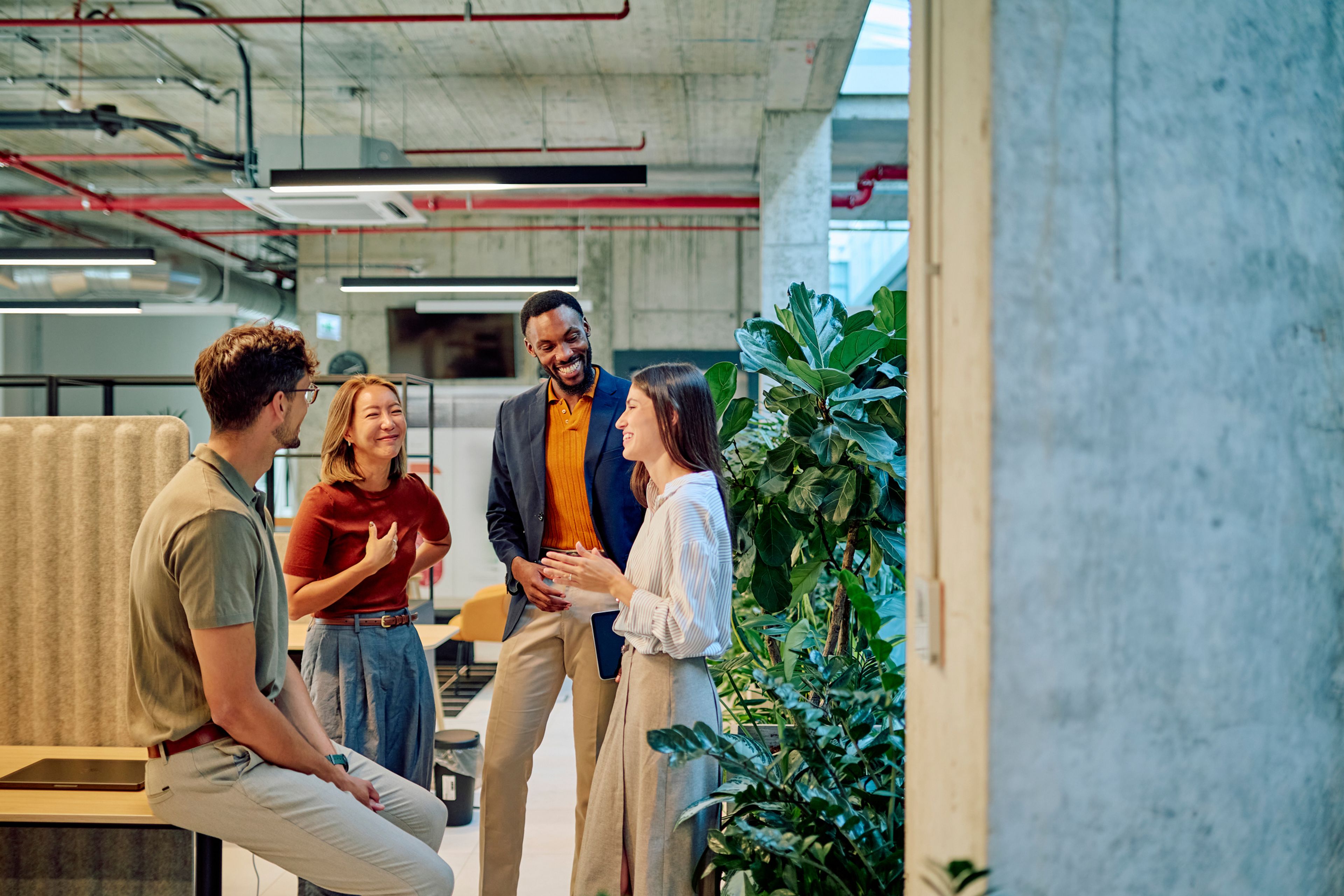 businesspeople talking and smiling during a meeting in a modern office with plants