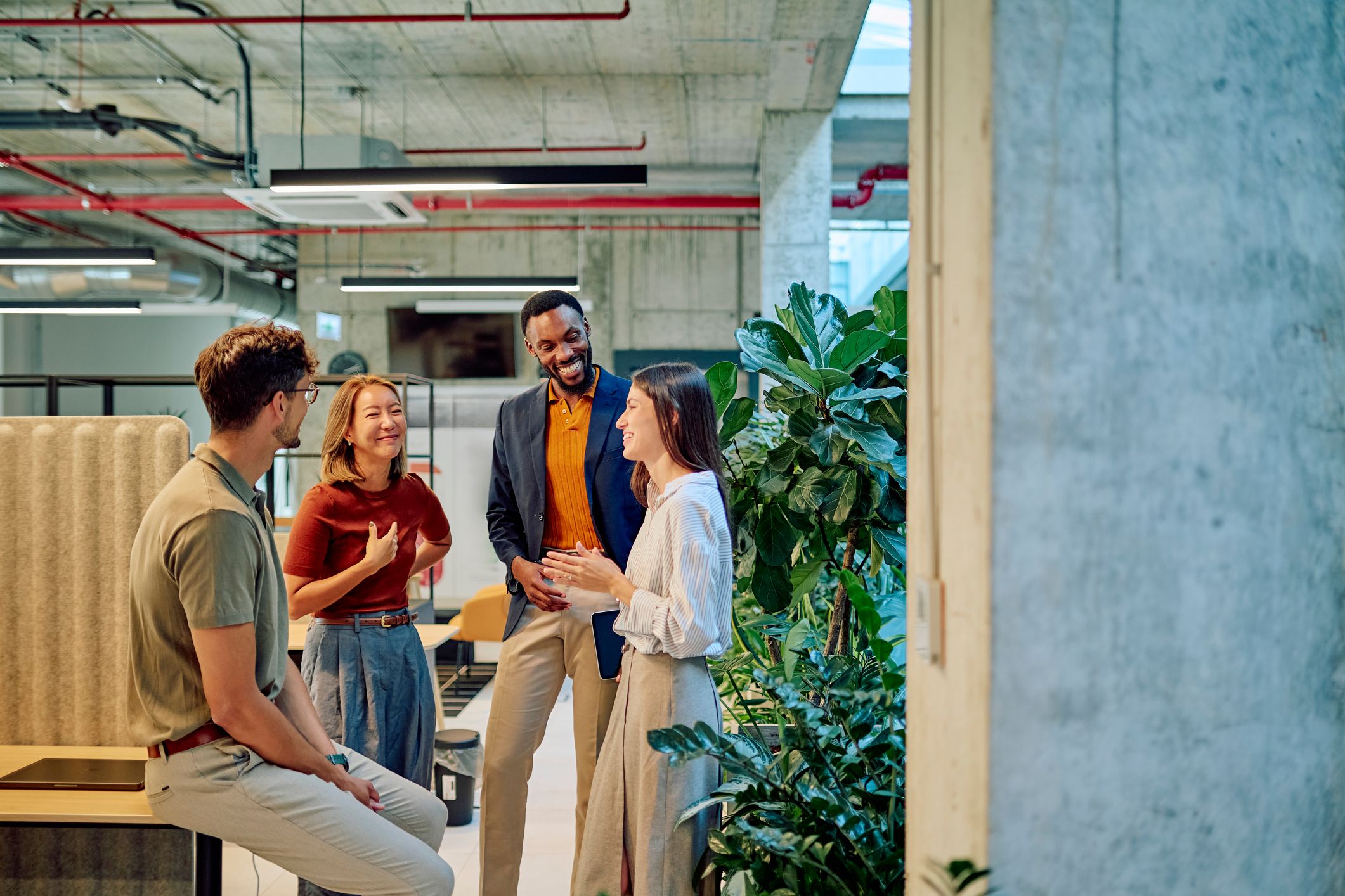 businesspeople talking and smiling during a meeting in a modern office with plants