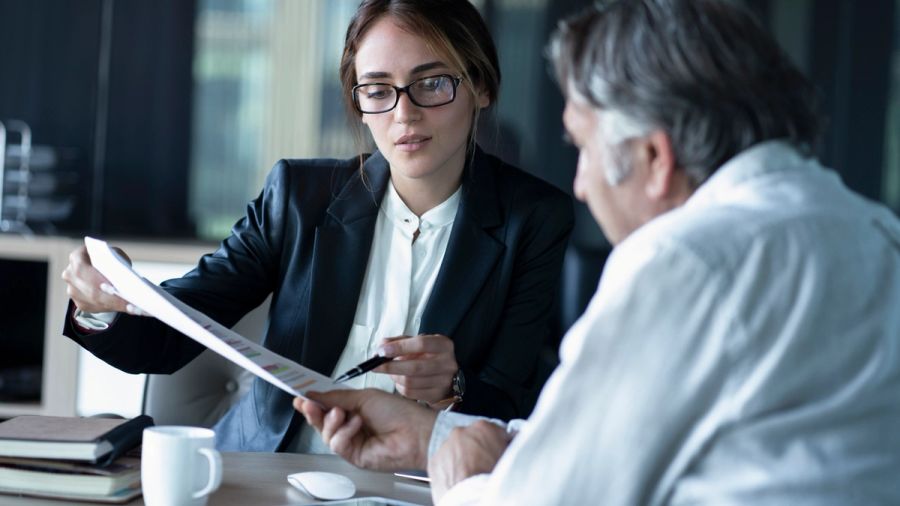 A young business woman shows an older man some financial projections.
