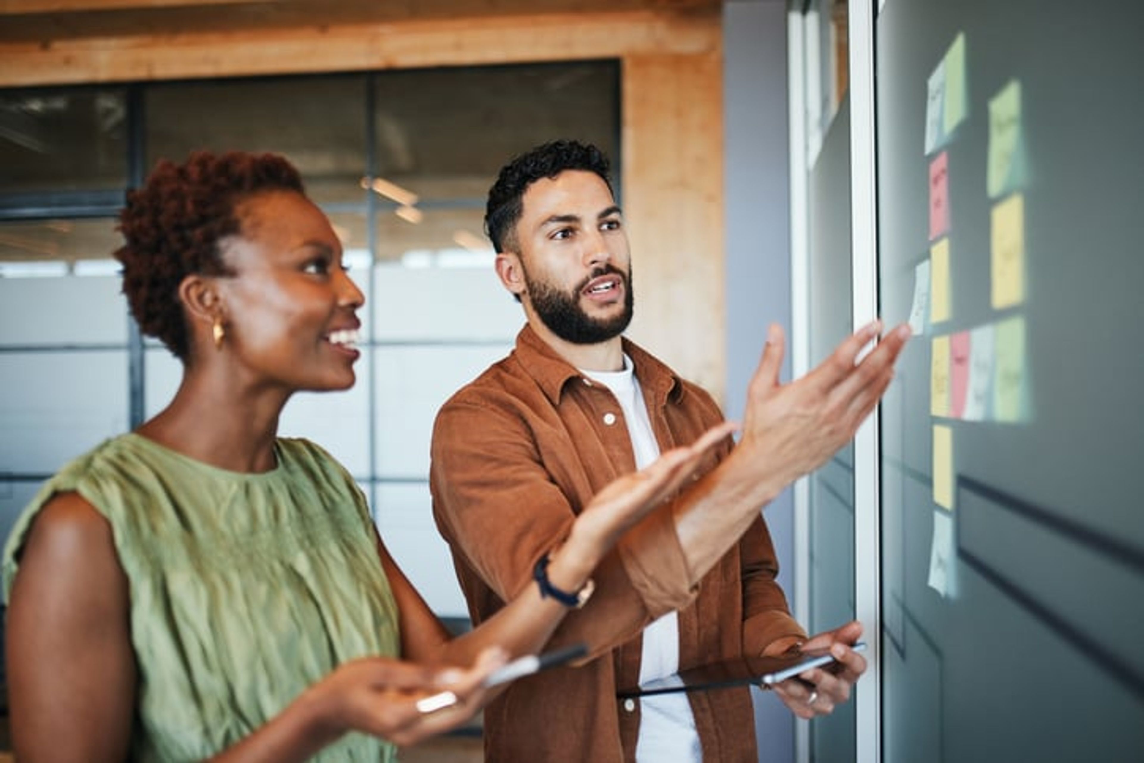 Two professionals look at a board, comparing multiple options.