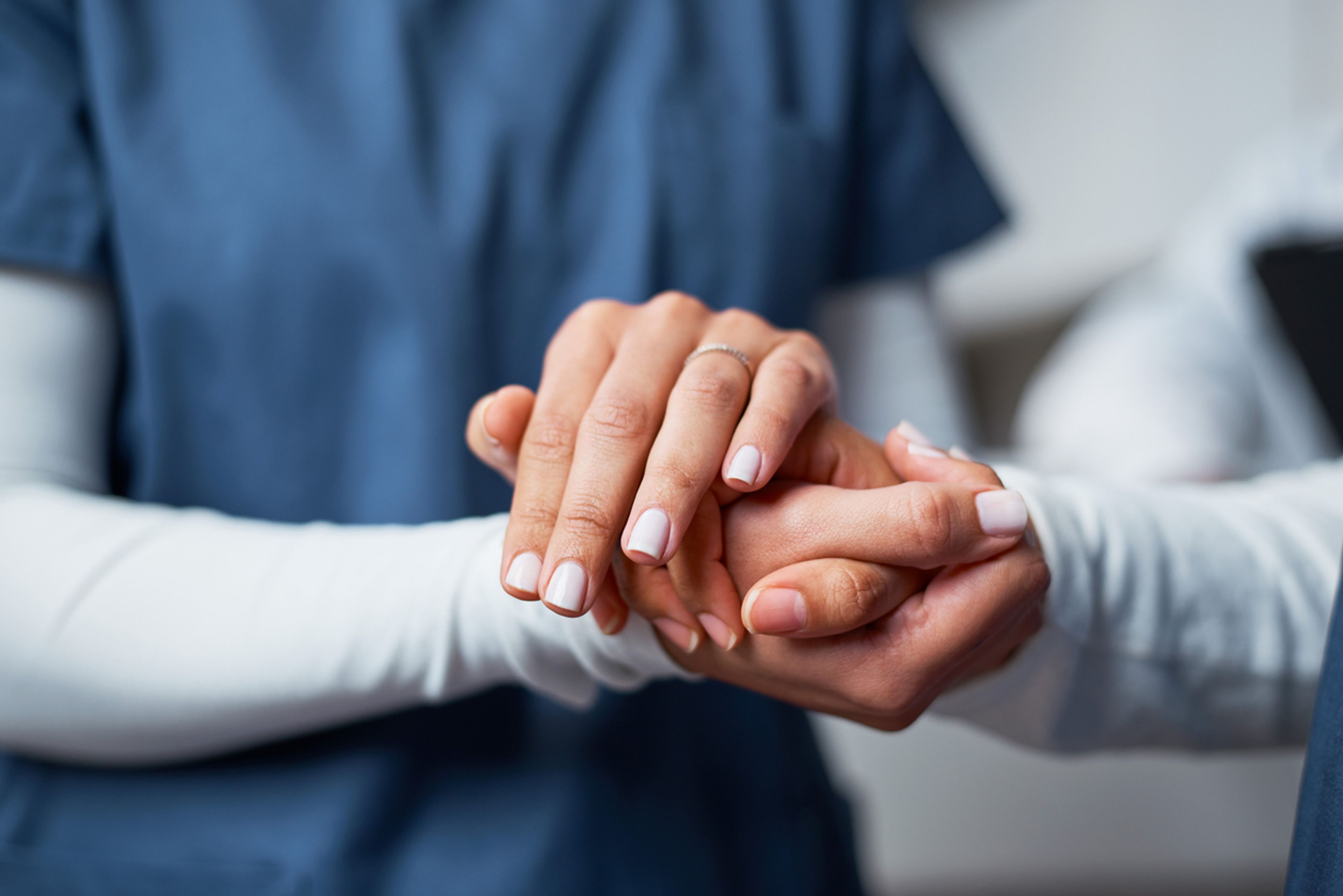 A nurse provides emotional support by gently holding a patient's hand.