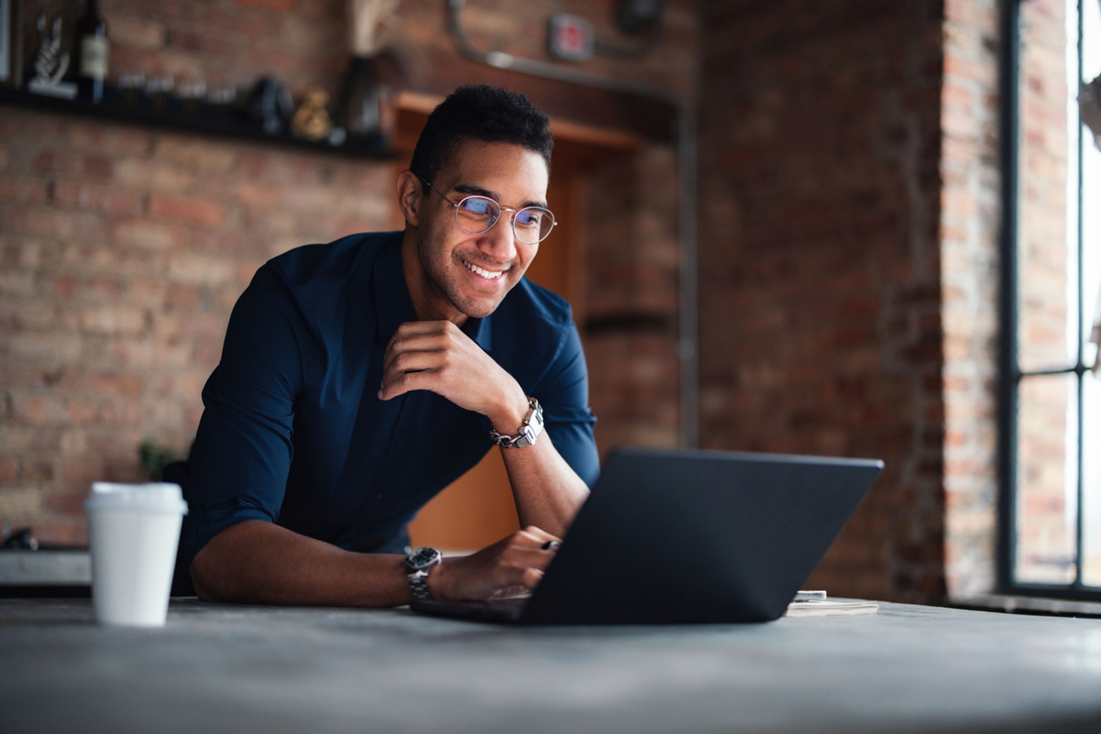 A professional individual working on a laptop in a bright, modern office.
