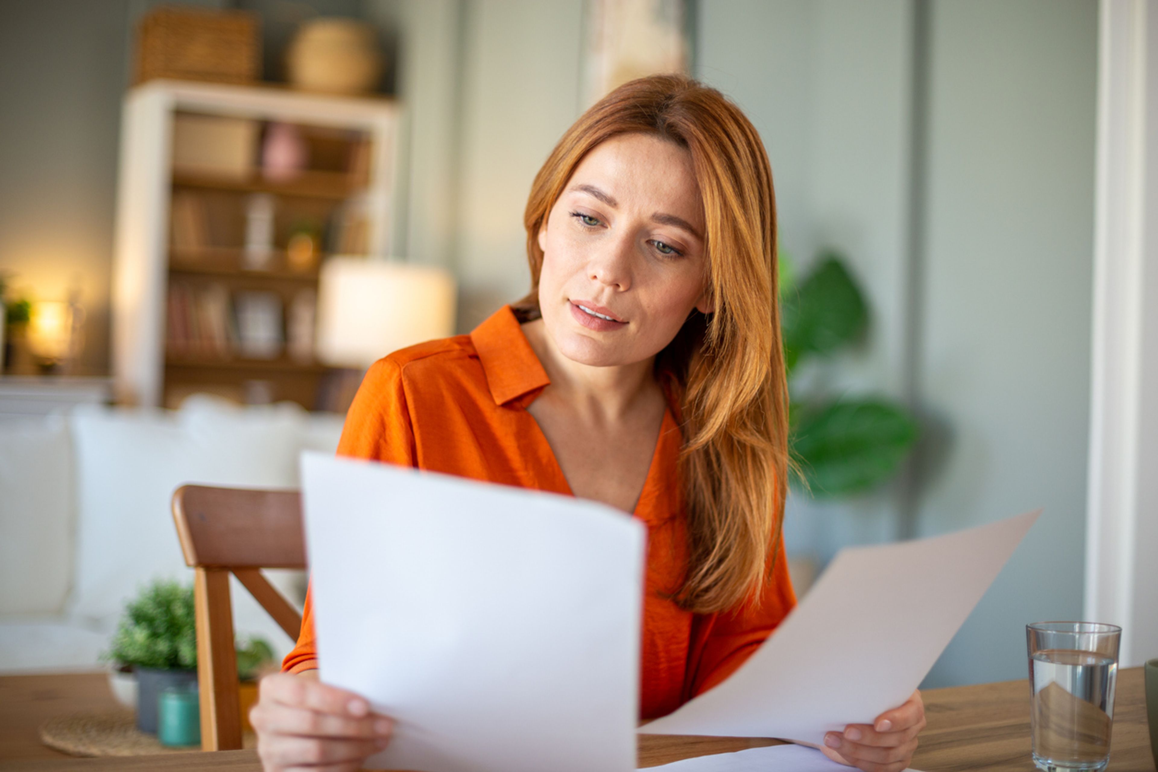 An annoyed woman sits a desk reading a multi-page NOID letter from USCIS.