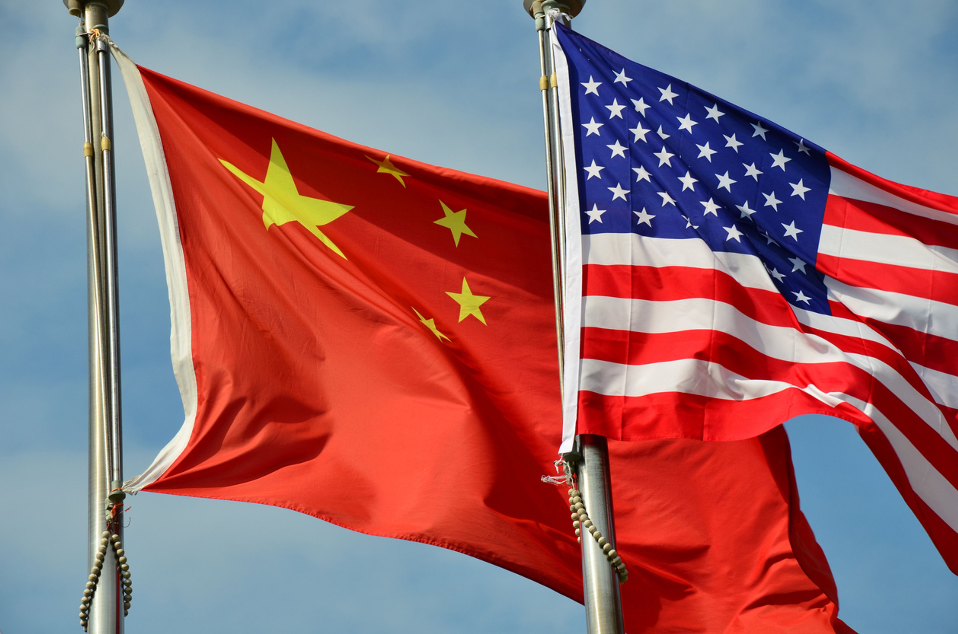 The flag of China flying in the wind next to the flag of the United states.