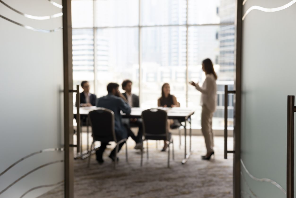 Silhouettes of businesspeople gathered in conference room for negotiation or seminar event
