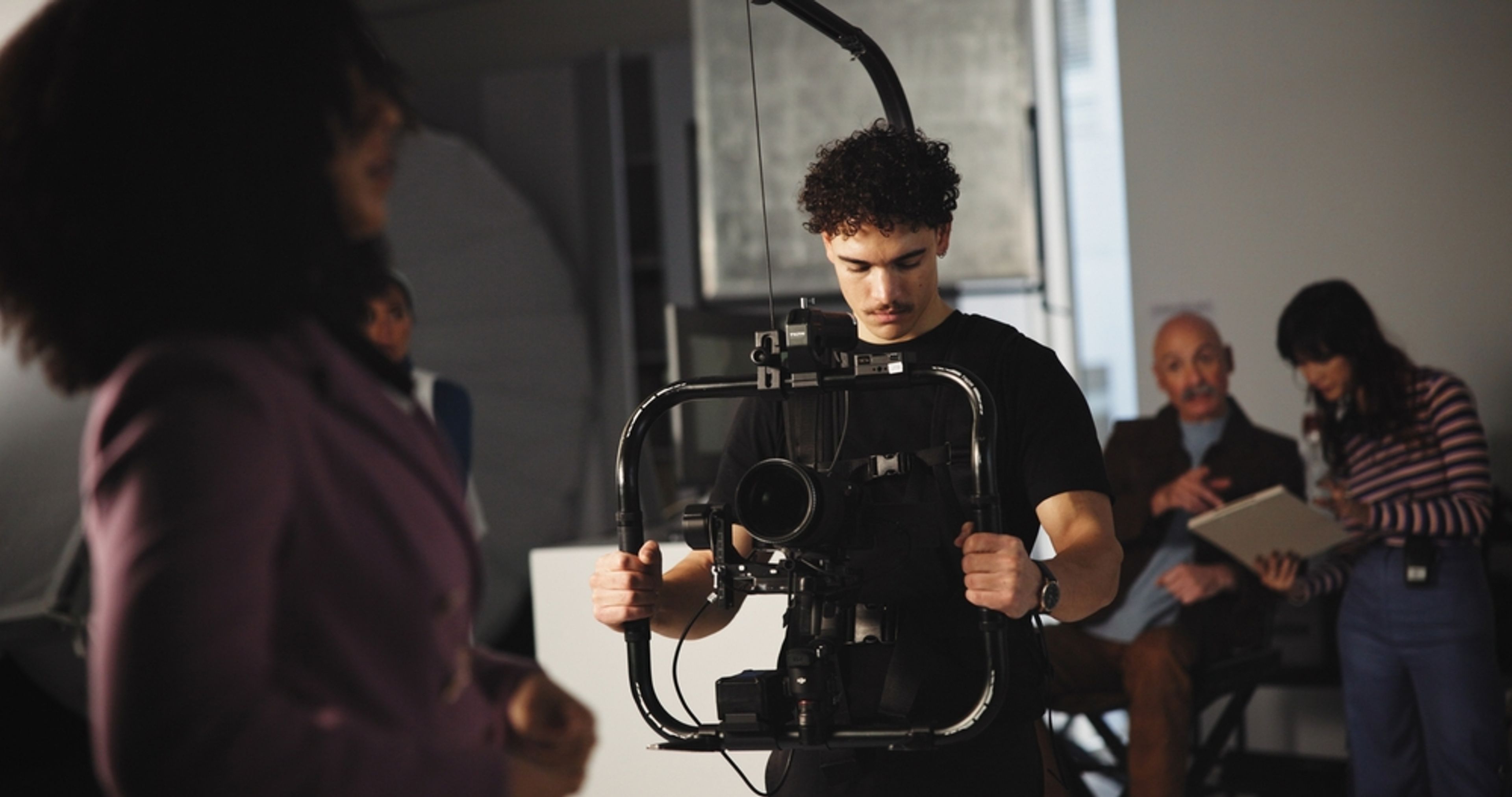 Cinematographer holding an image stabilizer device on a production set.