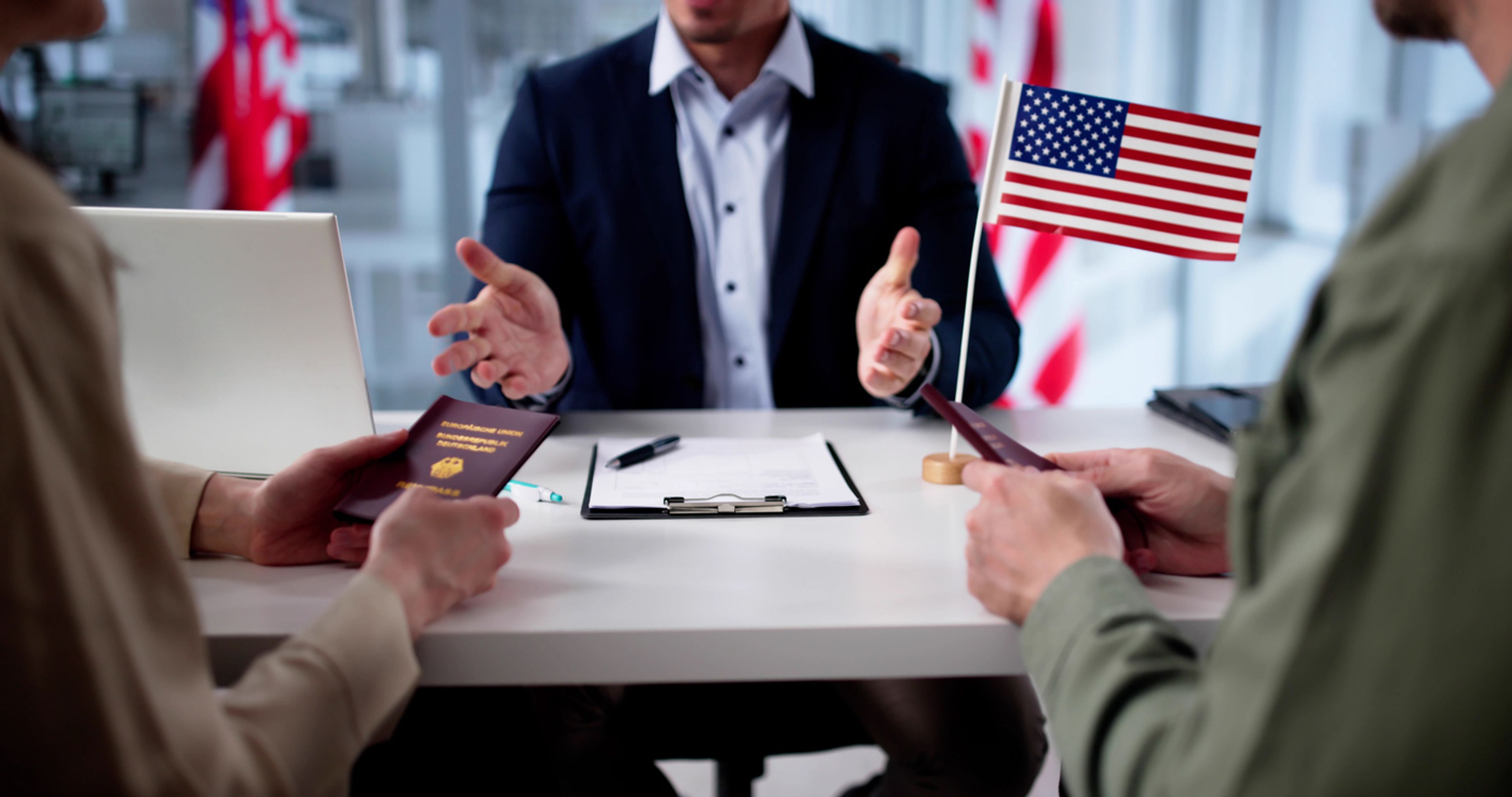 A man at a desk with a clipboard hands two people their passports.