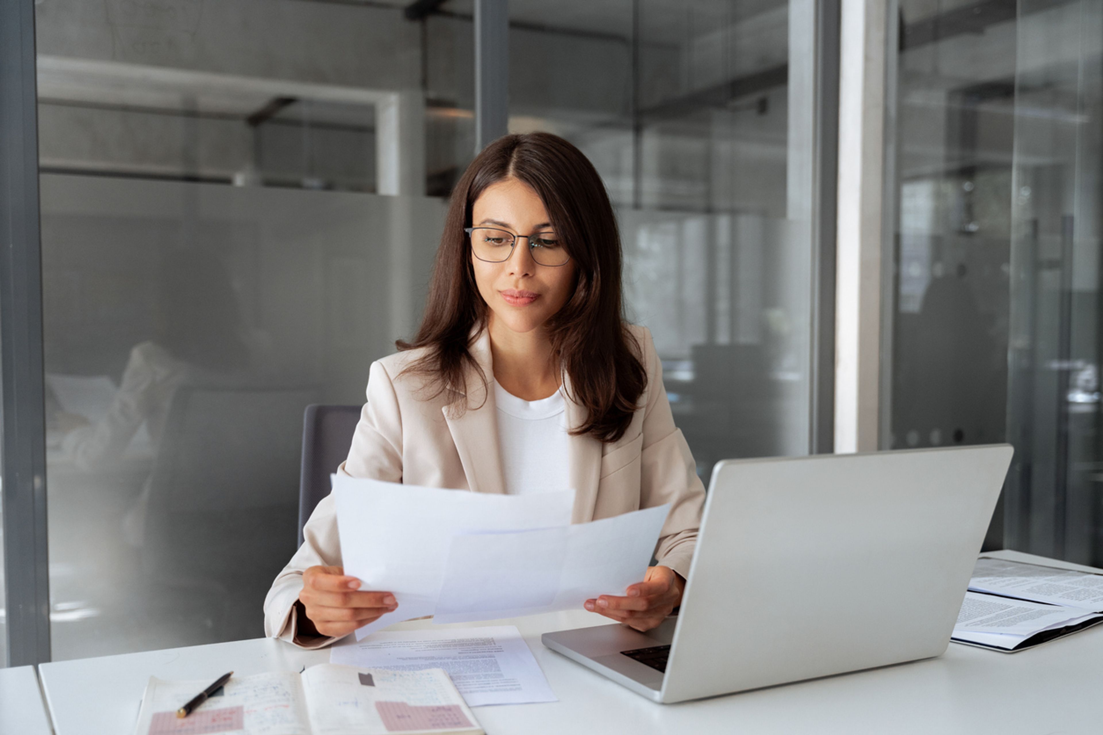 person on laptop reading documents in office