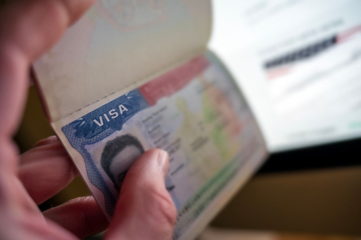 A closeup of a hand holding a U.S. visa, with the personal information blurred.