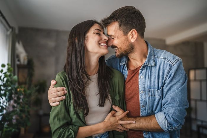 Portrait of a young couple smiling at each other while holding hands.