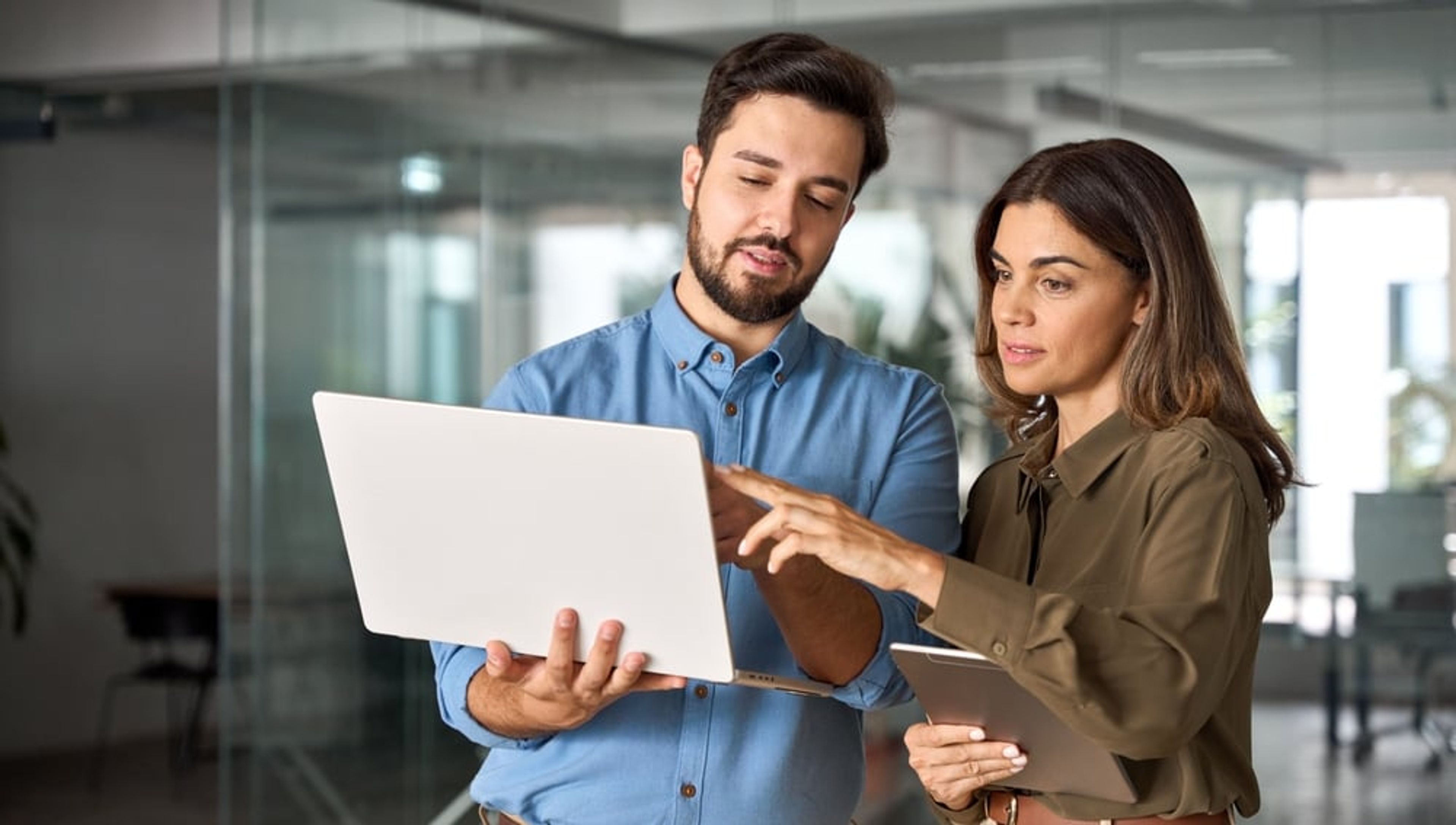 White-collar professionals looking at a laptop together in the office.