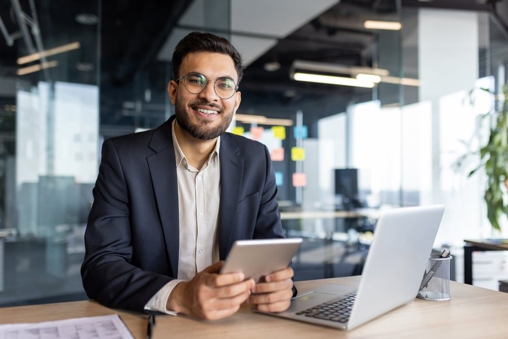 Worker in a modern startup office using his tablet and laptop.