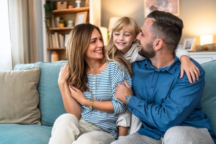Happy parents and young daughter relaxing together at home.