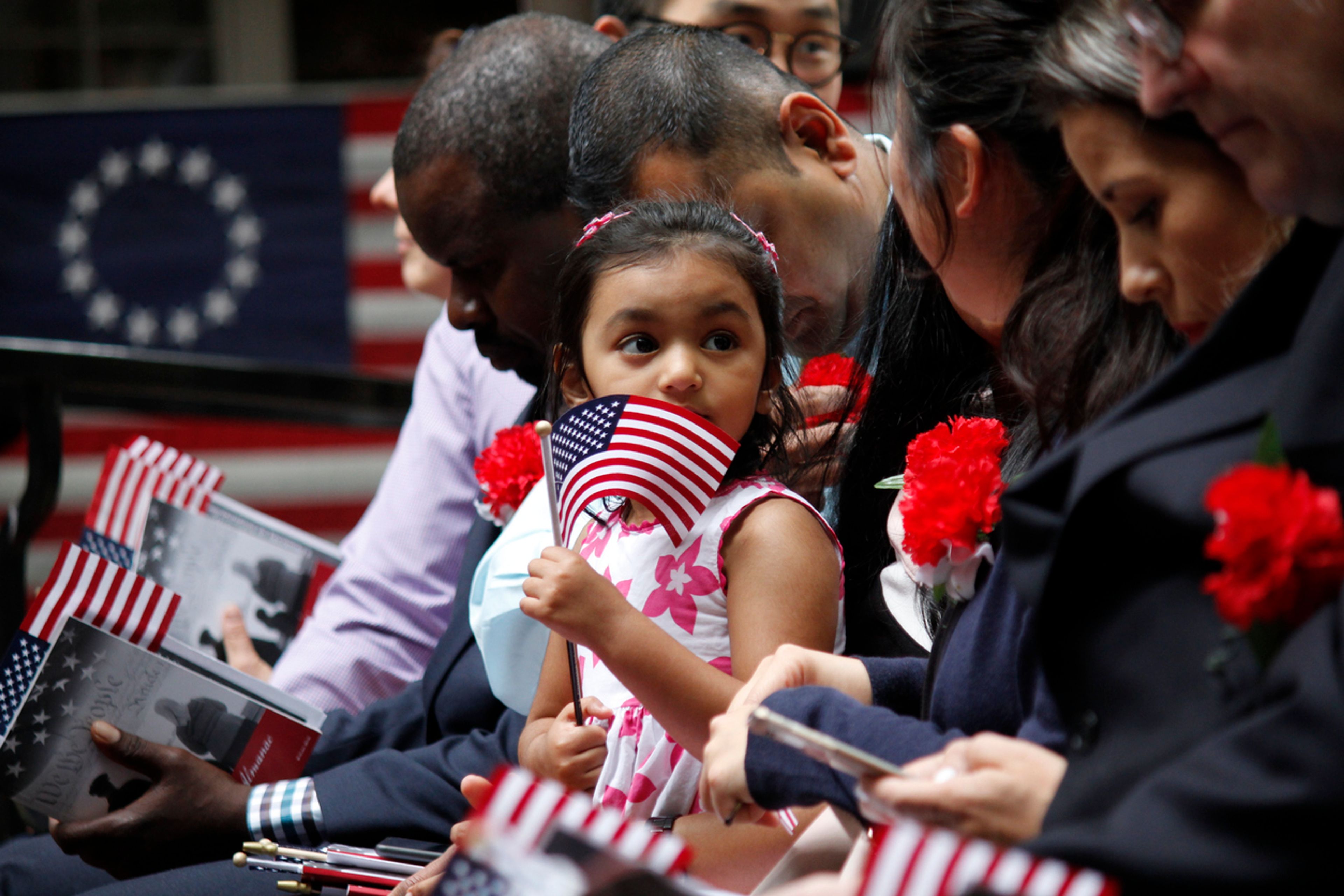 a child holds an american flag at a naturalization ceremony