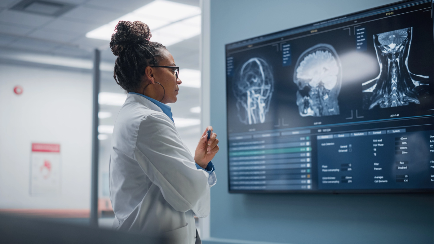 A physician reviewing head and neck scans on a medical monitor