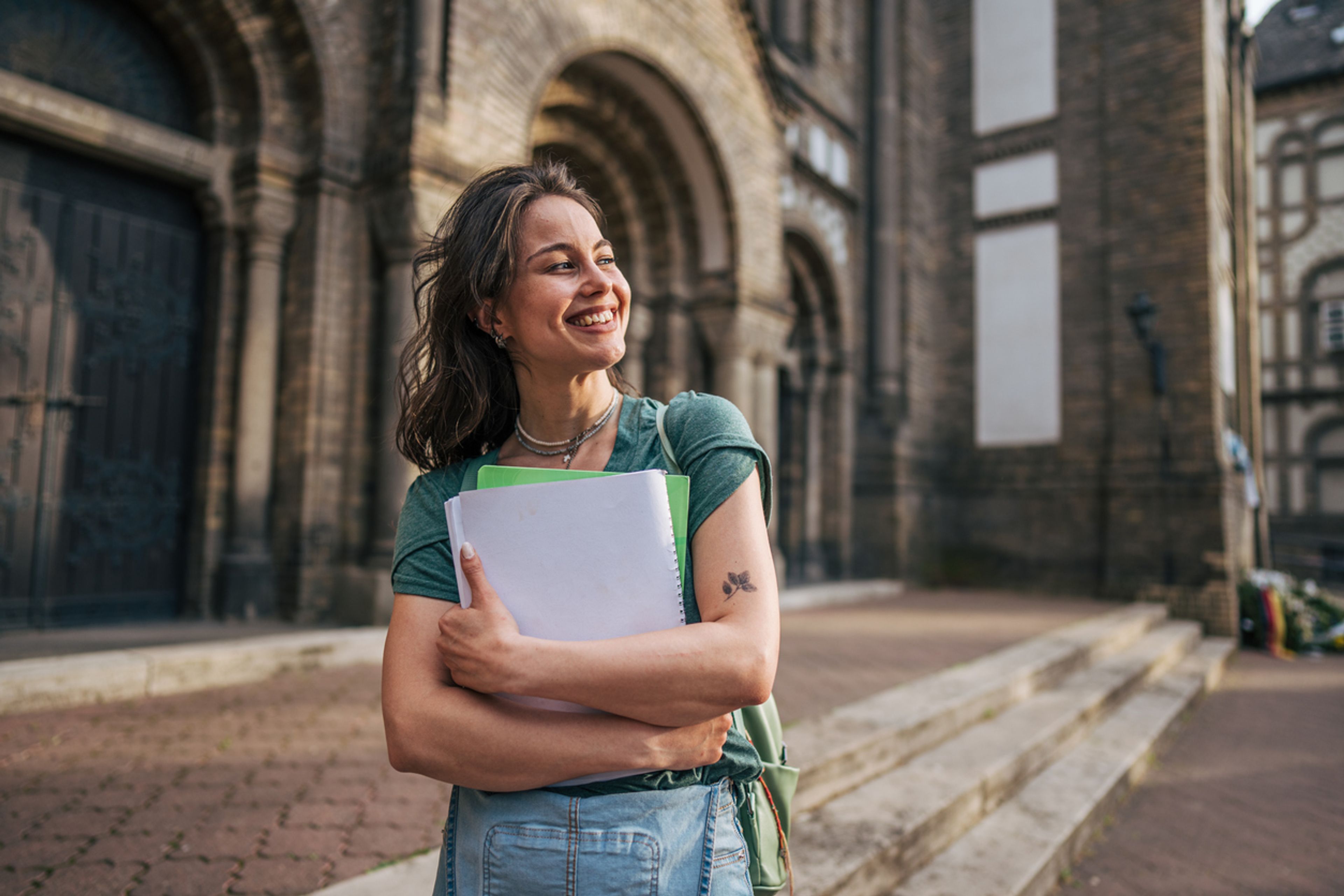 University student on campus holding her notebooks.