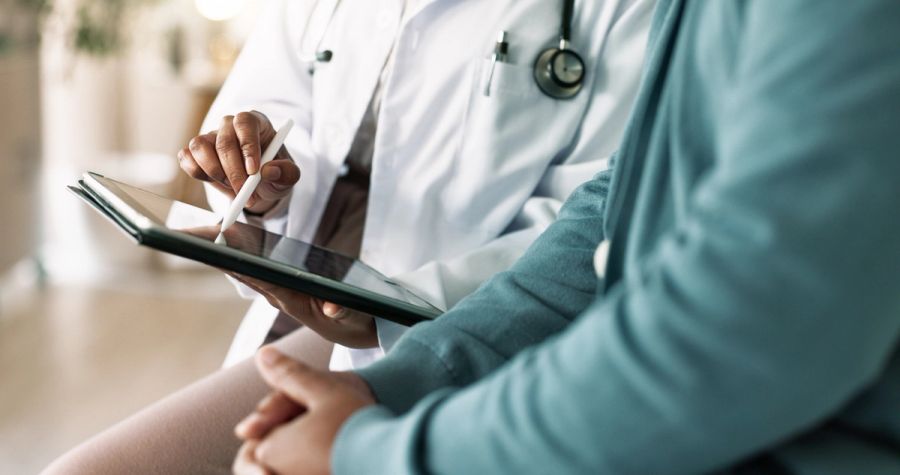 Closeup of doctor's hands reviewing a medical examination report with a patient.