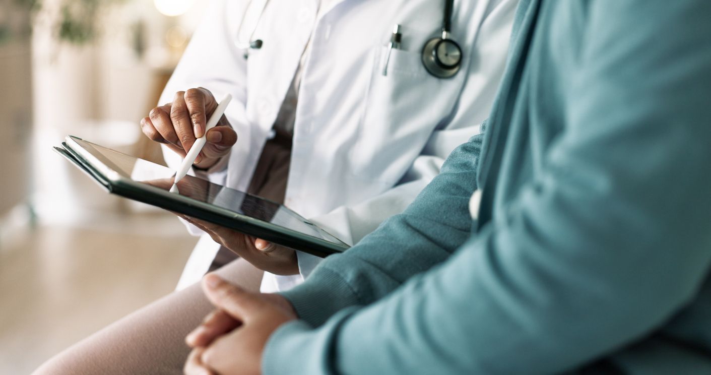 Closeup of doctor's hands reviewing a medical examination report with a patient.
