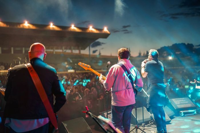 An older rock band performs live in front of a crowd after securing a P-1 visa.