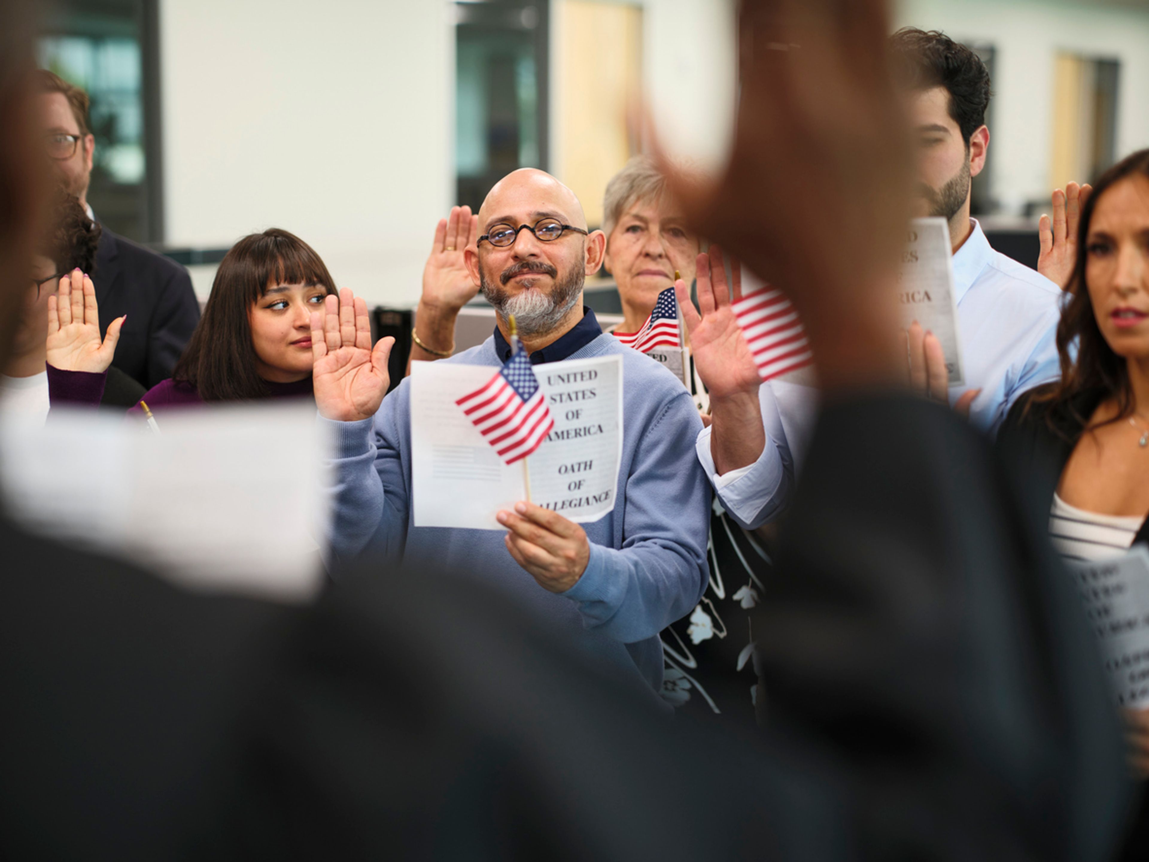 Group of people in a ceremony taking the United States Naturalization Oath of Allegiance to become citizens.