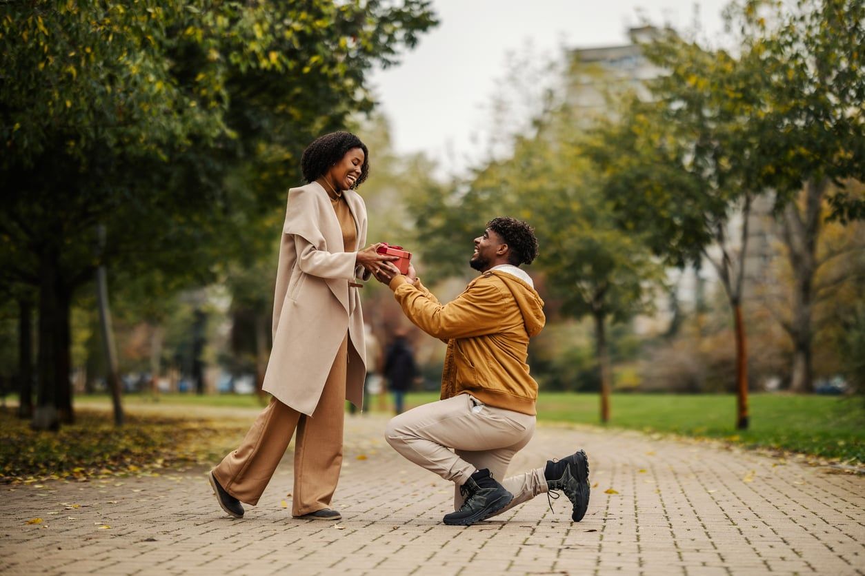 A man proposing to his fiancee in the park.