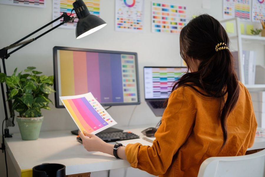 Graphic designer reviewing printed color samples at a studio desk.