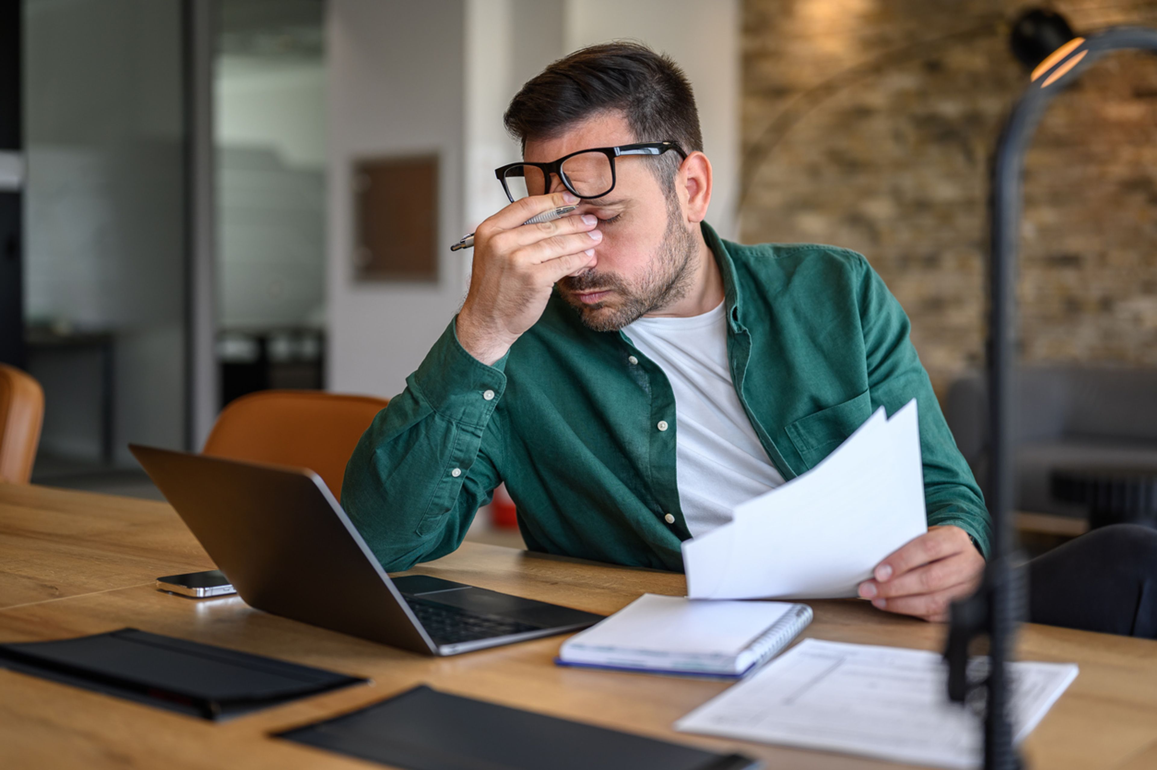 Concerned man looking over documents at his desk.