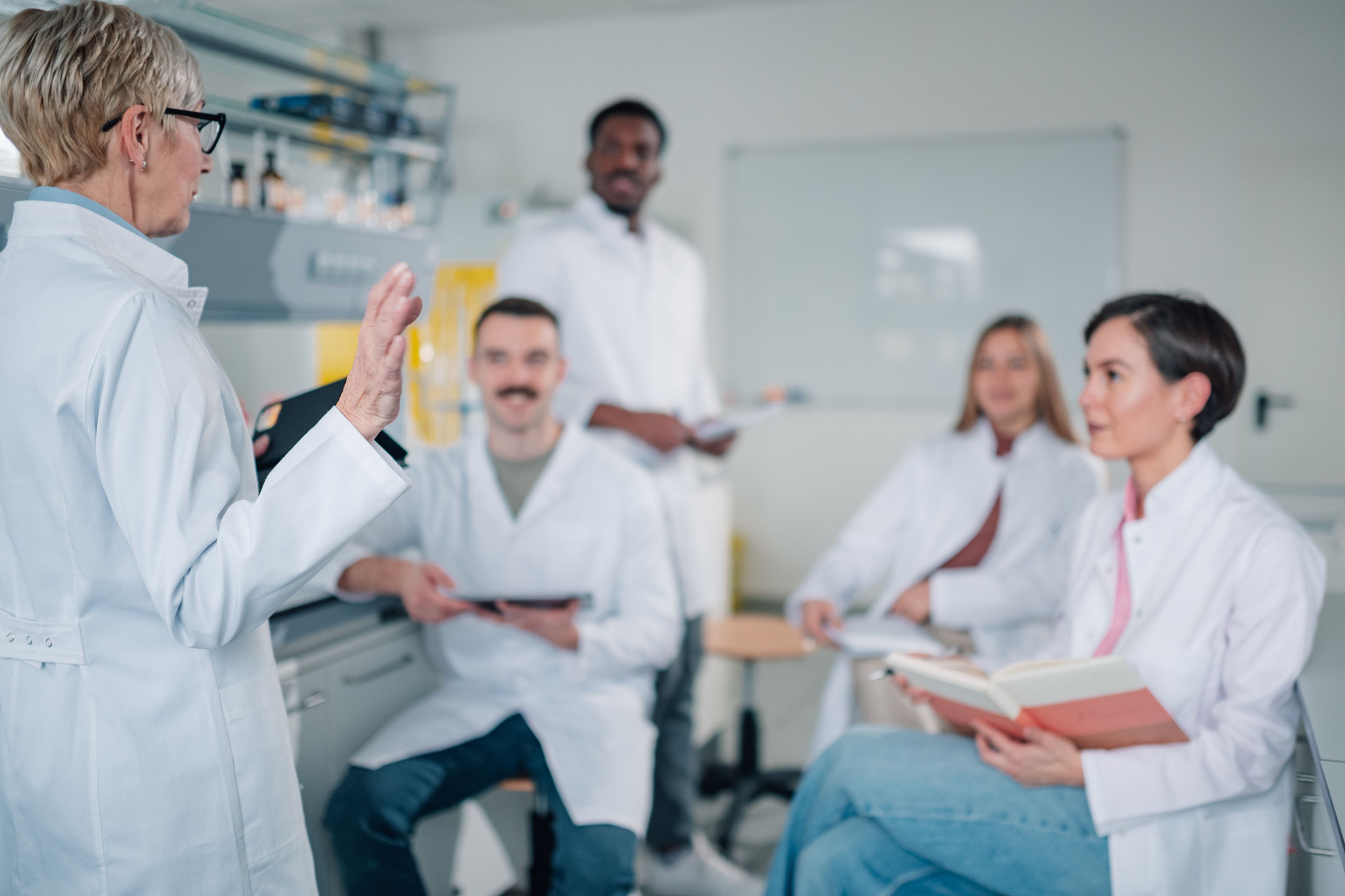Researchers in lab coats discussing a project together in a university laboratory.